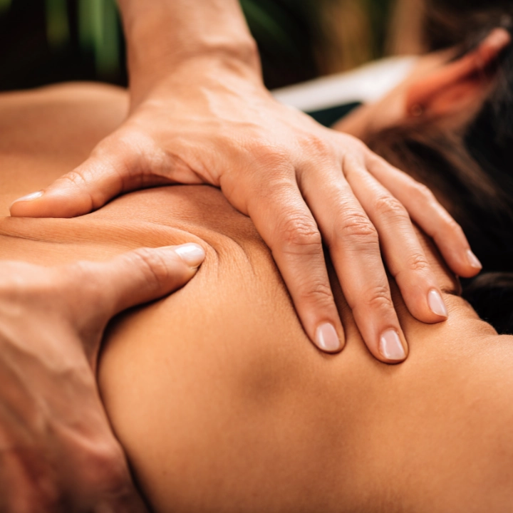 Therapist working with both hands along a client’s upper back and shoulder
